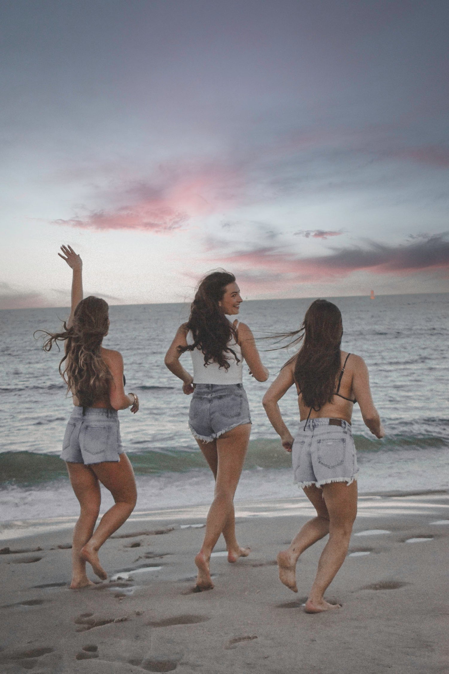 Girls running on the beach at sunset in clothing from Rekindled Rehoboth Beach